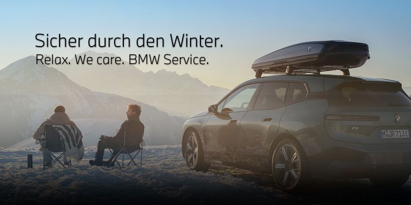 BMW Service. Sicher in den Winter. Zwei Männer neben einem Fahrzeug im Schnee.