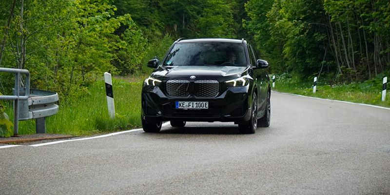 Der vollelektrische BMW iX1 fahrend auf der Straße